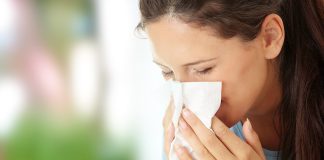 Ženska si briše nos zaradi alergijskega rinitisa z vodenim izcedkom.