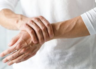 Odpravimo bolečino v sklepih Oseba si zaradi bolečine drži zapestje in sklepe rok