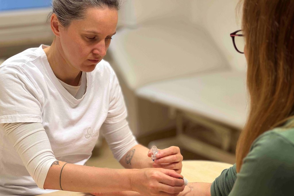 Medicinska sestra izvaja kožni alergološki test na pacientki.