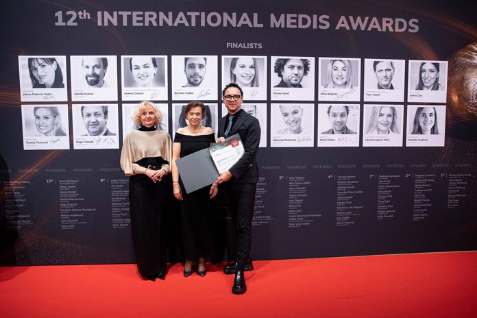 Trije udeleženci pred steno finalistov 12. International Medis Awards držijo priznanje.